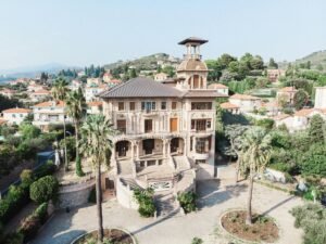 Picturesque scenery of aged Baroque styled Villa Grock and Museo del Clown located in hilly terrain near typical residential houses against cloudless blue sky in Italy