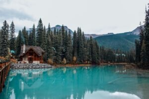 Beautiful serene lake with cabin and pine forest in a mountainous landscape.